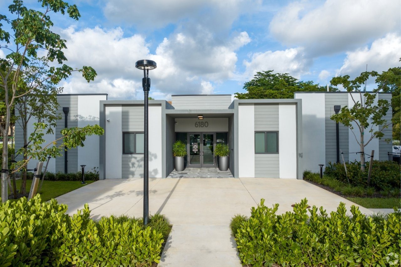 The image shows a modern building with a glass entrance and a sign that reads "B160".